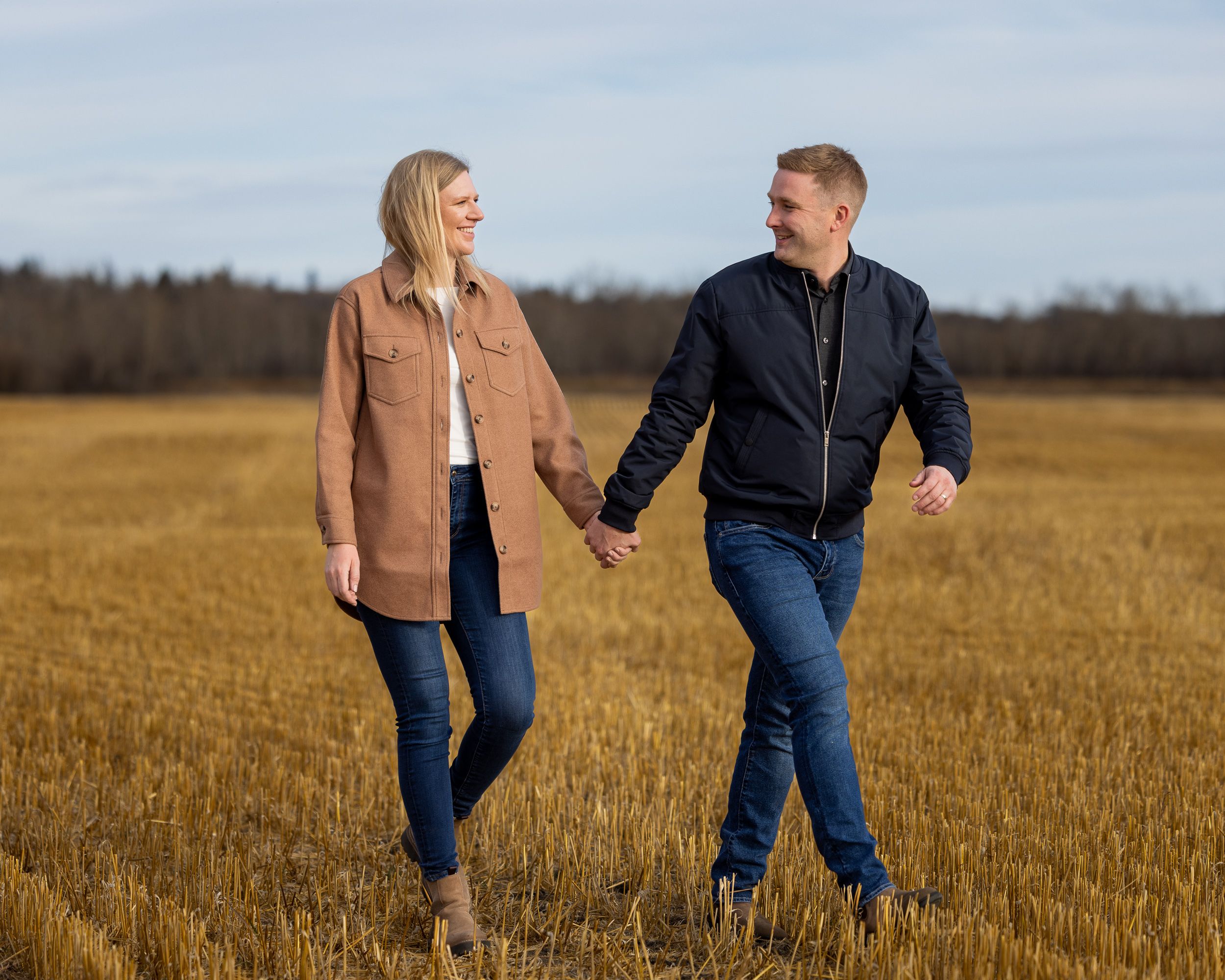 Couple walking hand in hand through a harvested wheat field