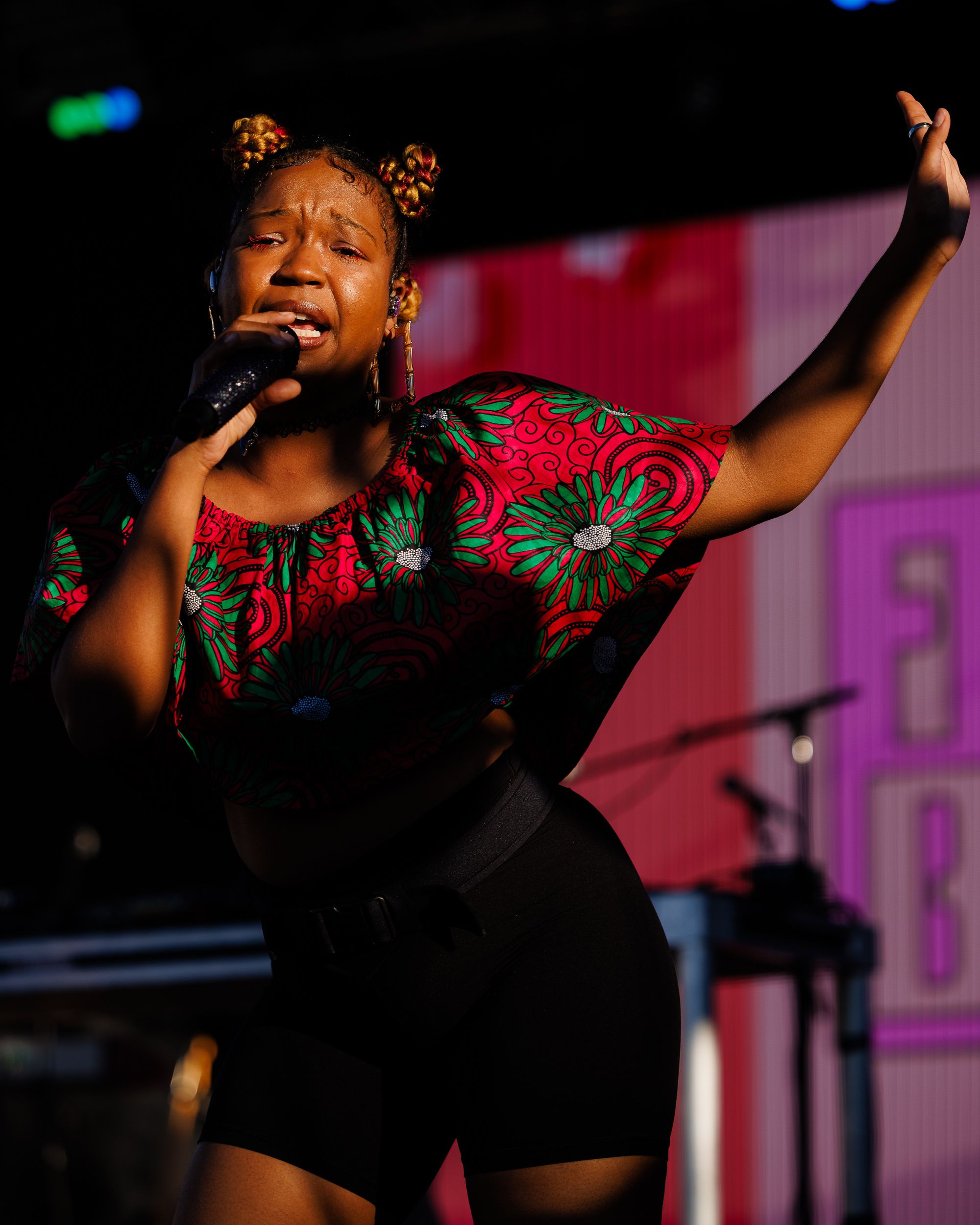 Singer in a bold print performing on a festival stage