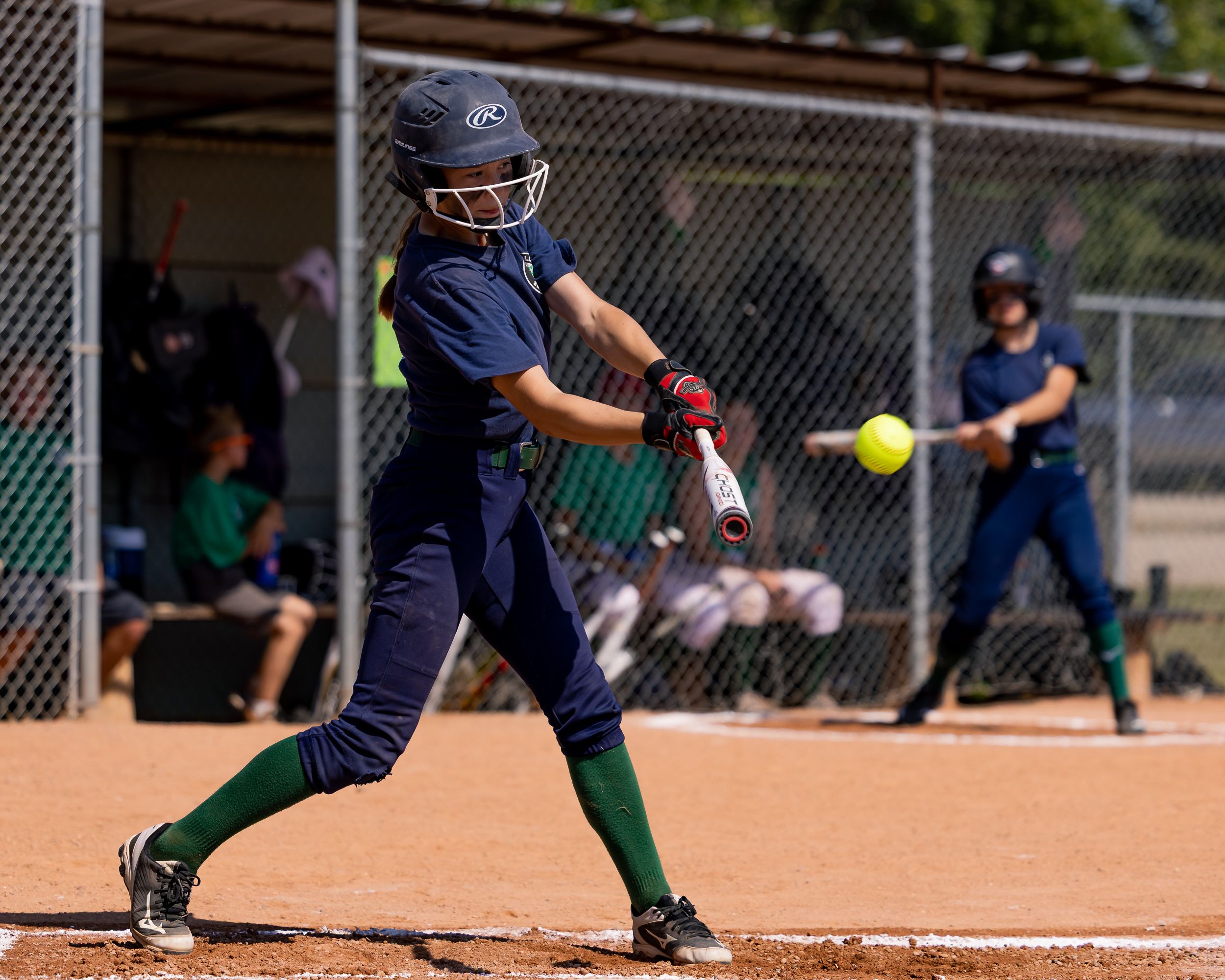 Softball batter making contact with the ball mid-swing