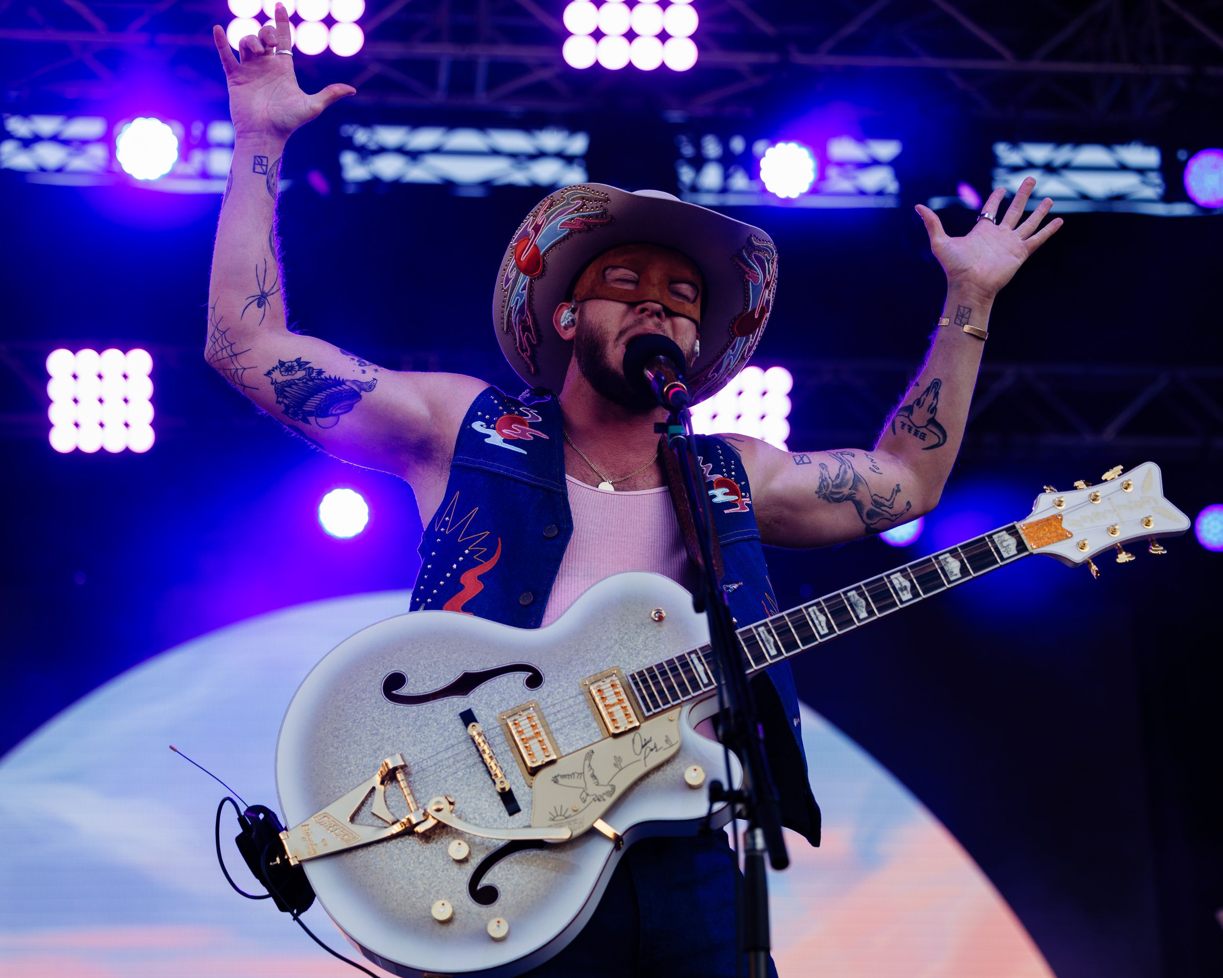 Performer with arms raised holding a white guitar on stage
