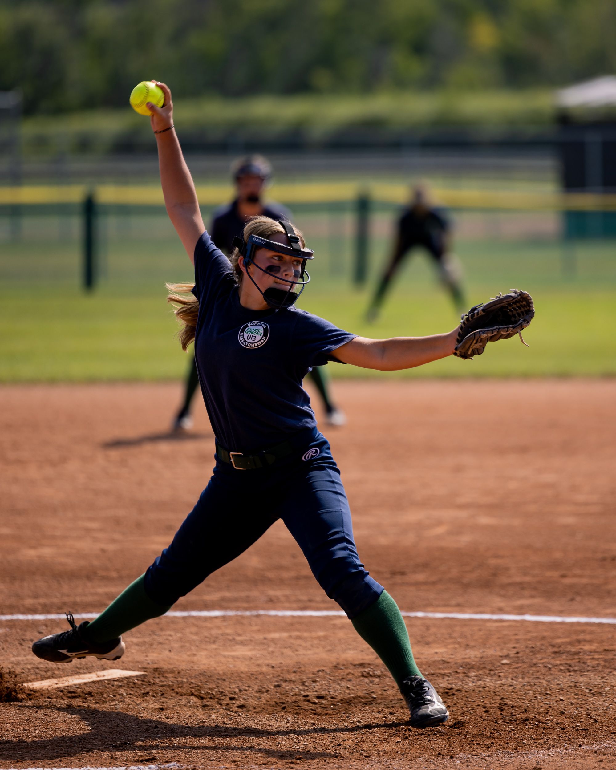 Softball pitcher catching the ball in her glove mid-play