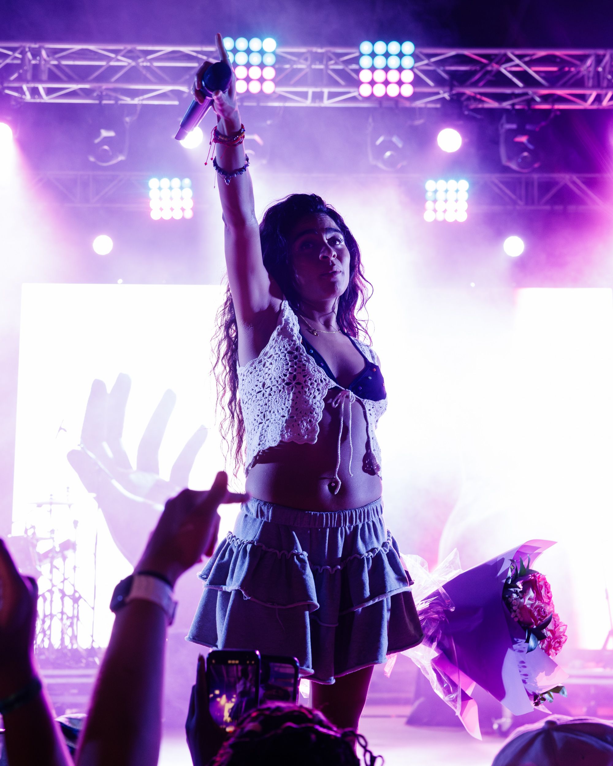 Performer dancing above the crowd in purple stage light