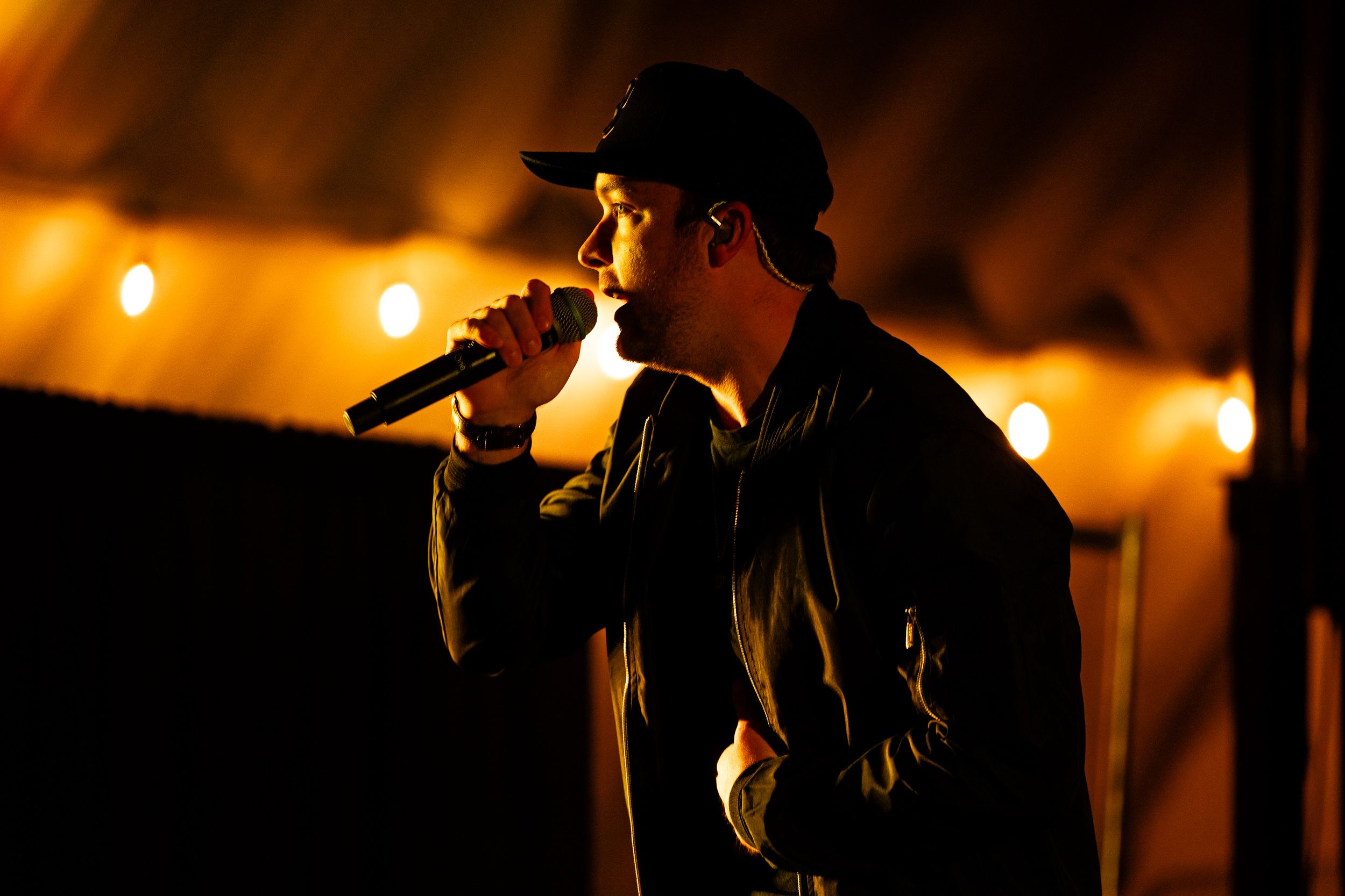 Musician singing under warm string lights at an album release show