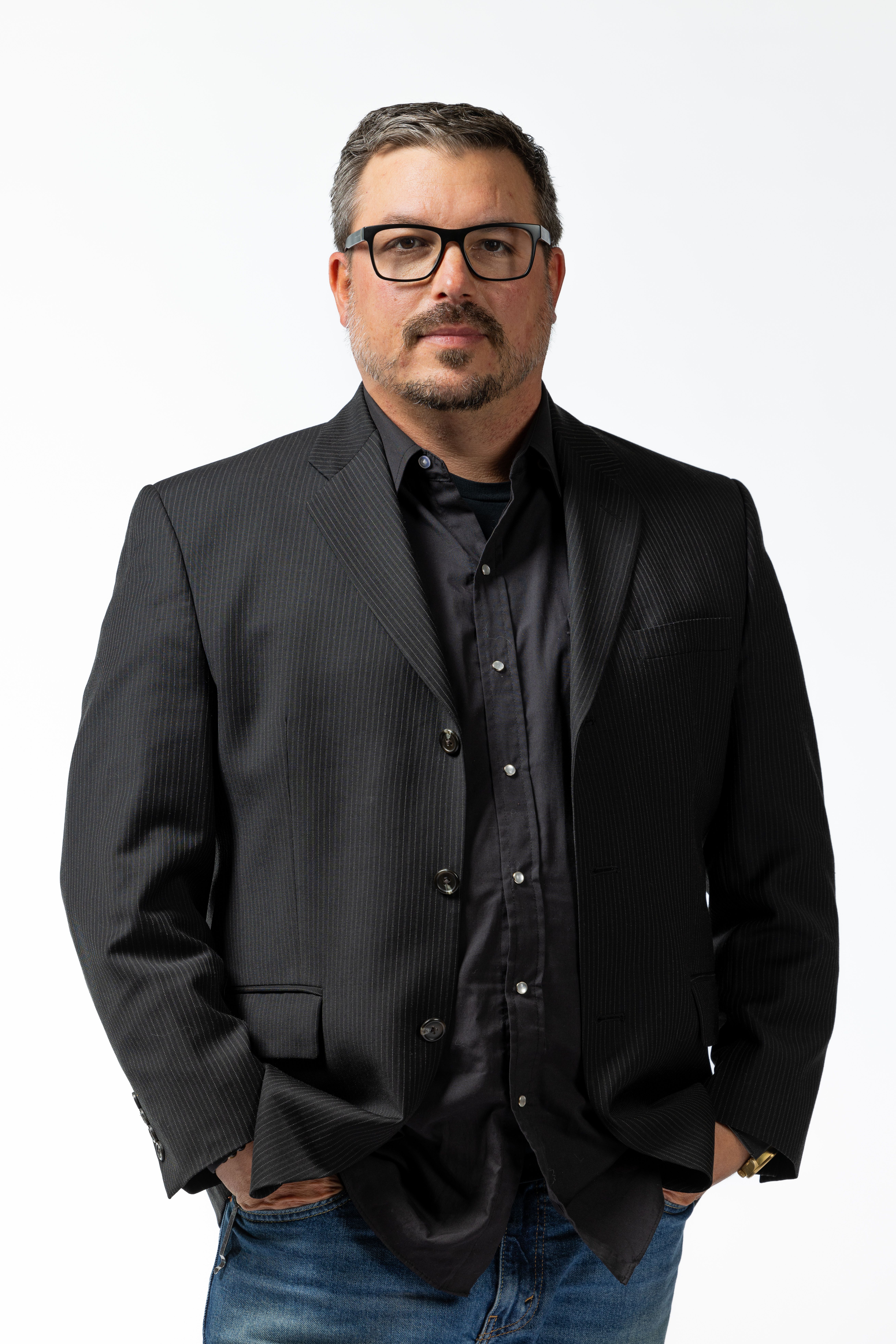 Professional headshot of a man in a dark blazer