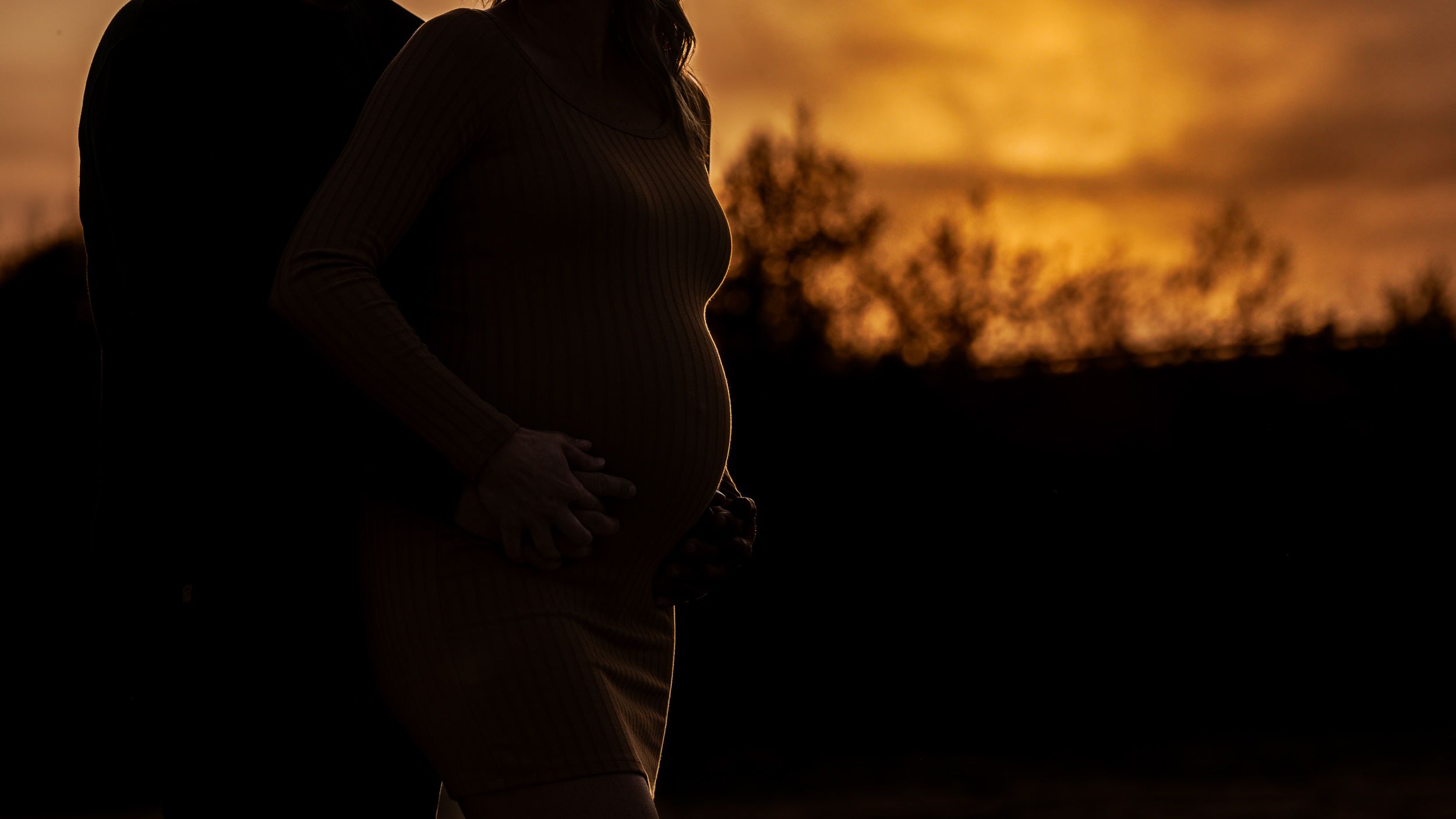 Golden-hour maternity portrait in an open Saskatchewan field at sunset
