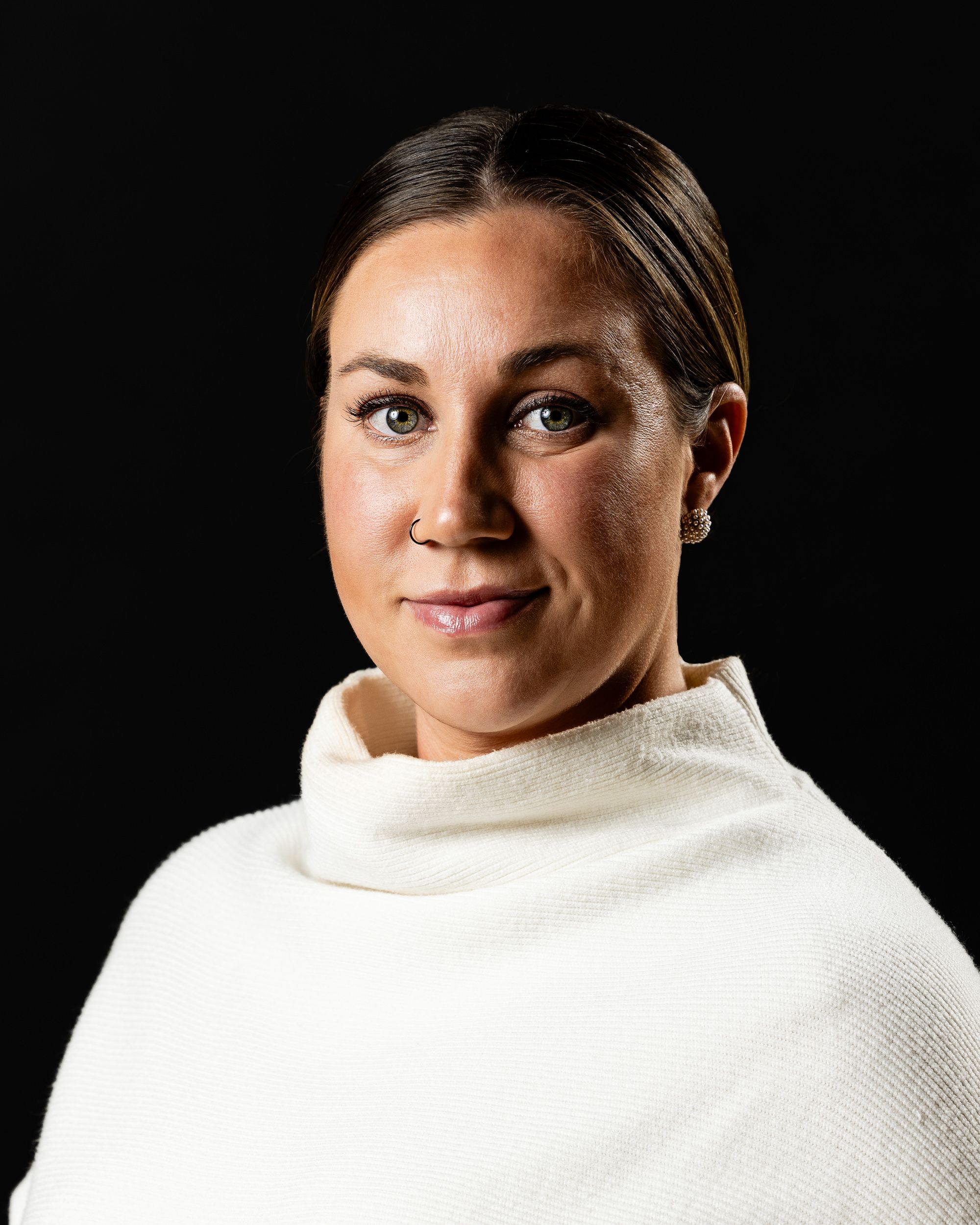 Professional portrait of a woman in a white turtleneck on a dark background