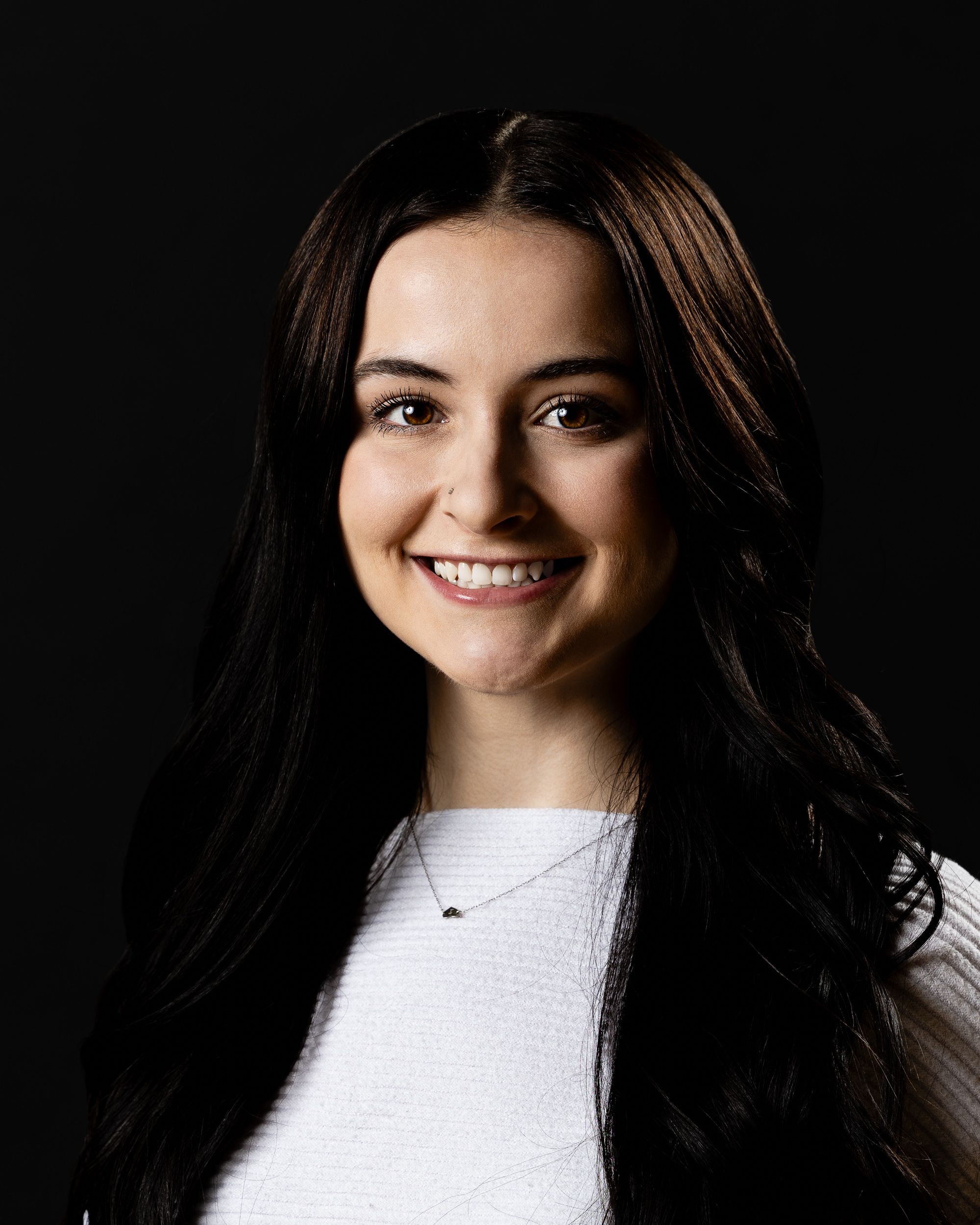 Dark-background professional headshot of a smiling young woman