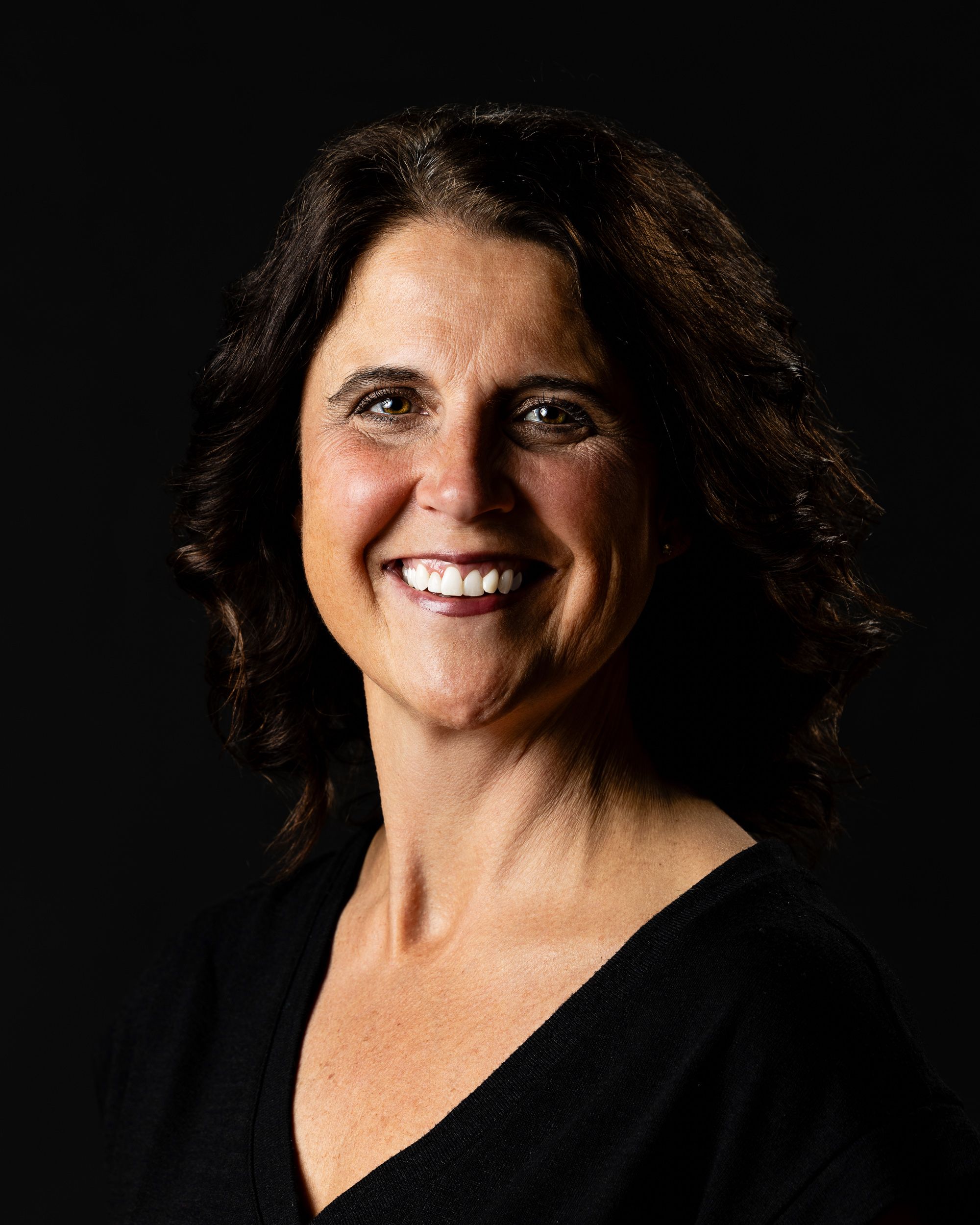 Dark-background professional portrait of a smiling woman