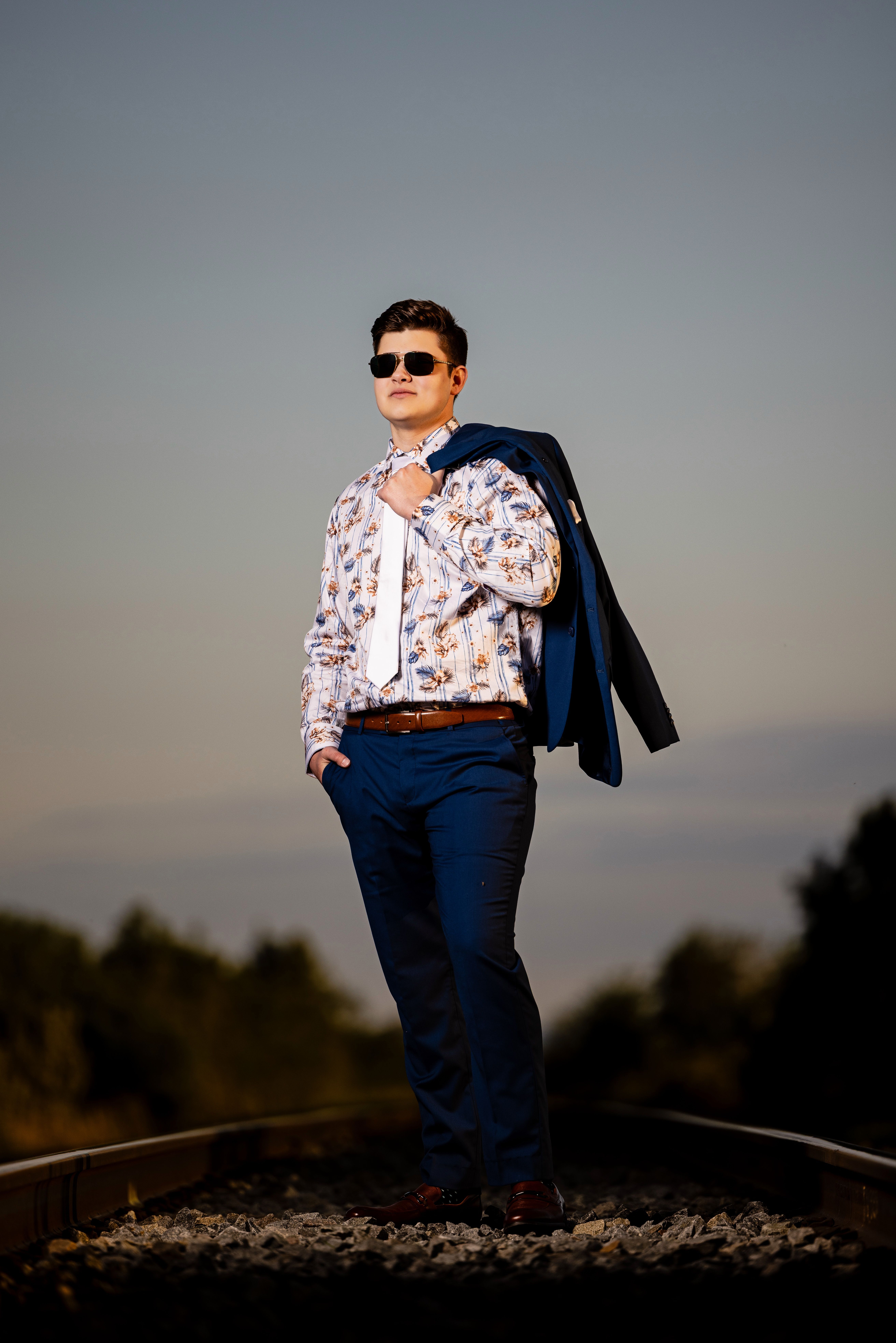 Grad on railway tracks at dusk with his jacket over his shoulder