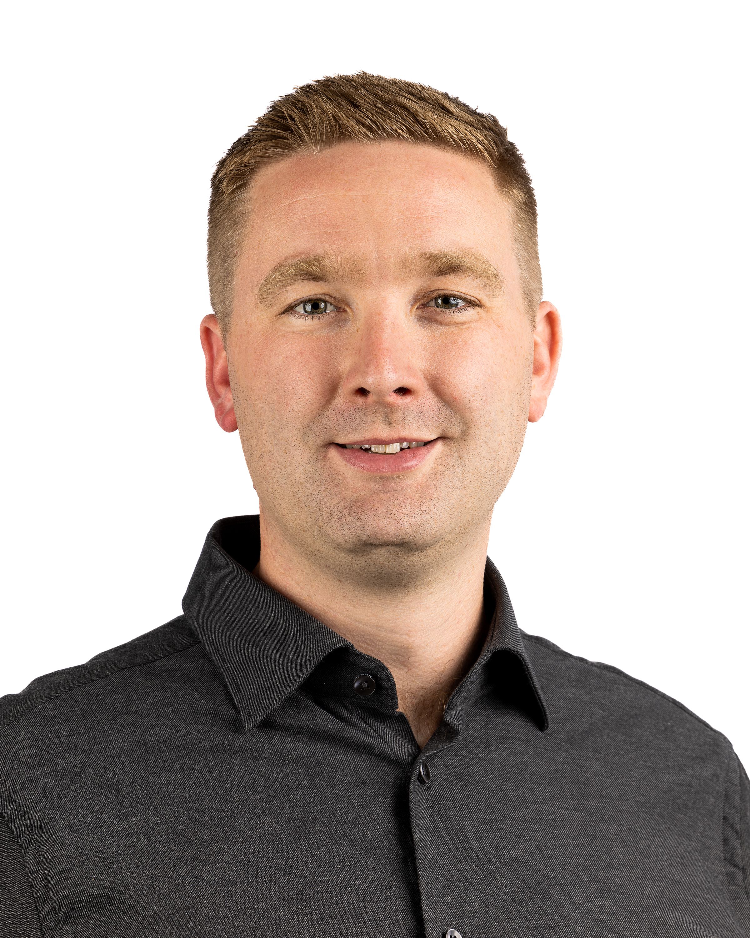 Smiling professional headshot of a man in glasses and a patterned shirt