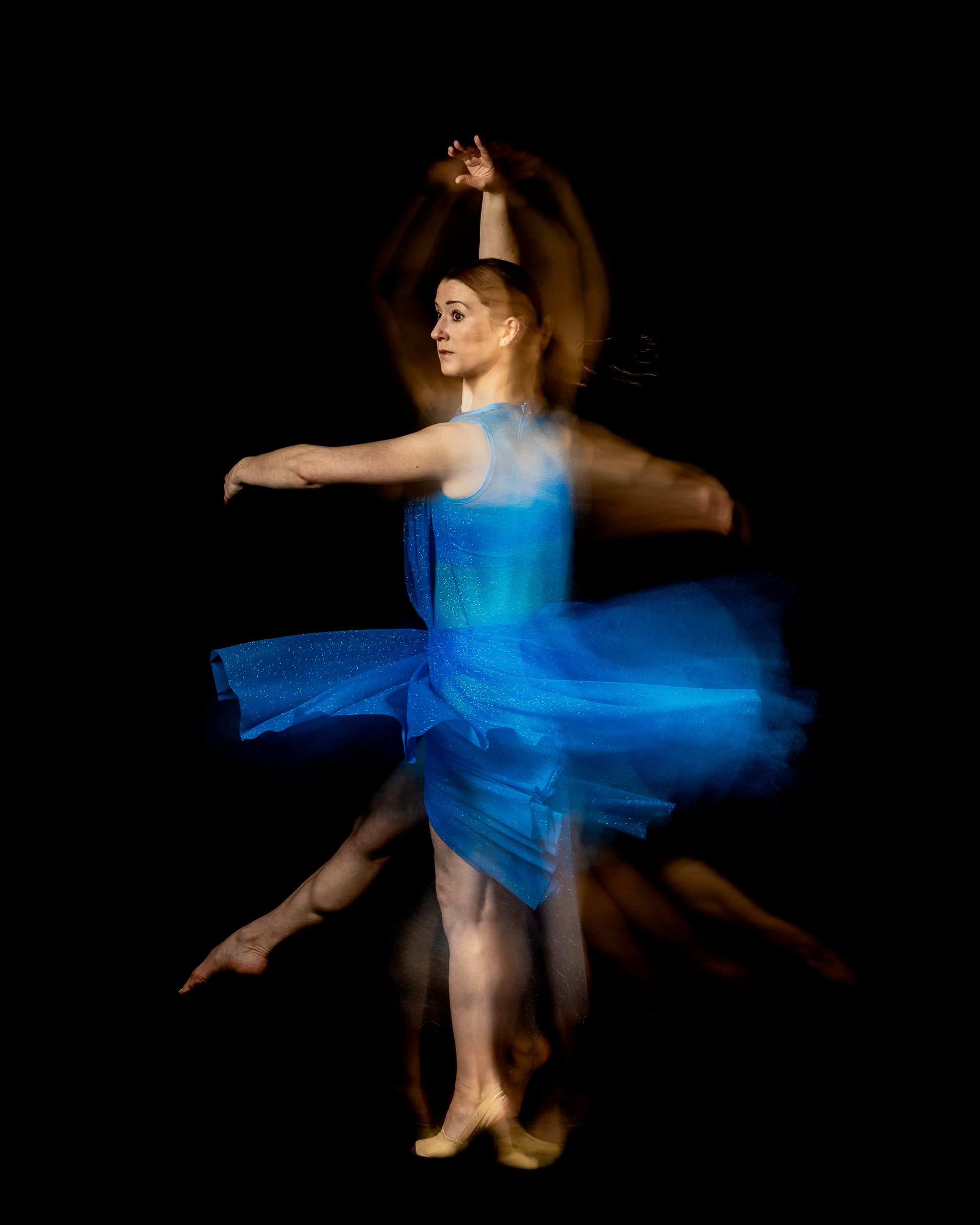 Dancer in blue spinning with motion trails on a dark stage