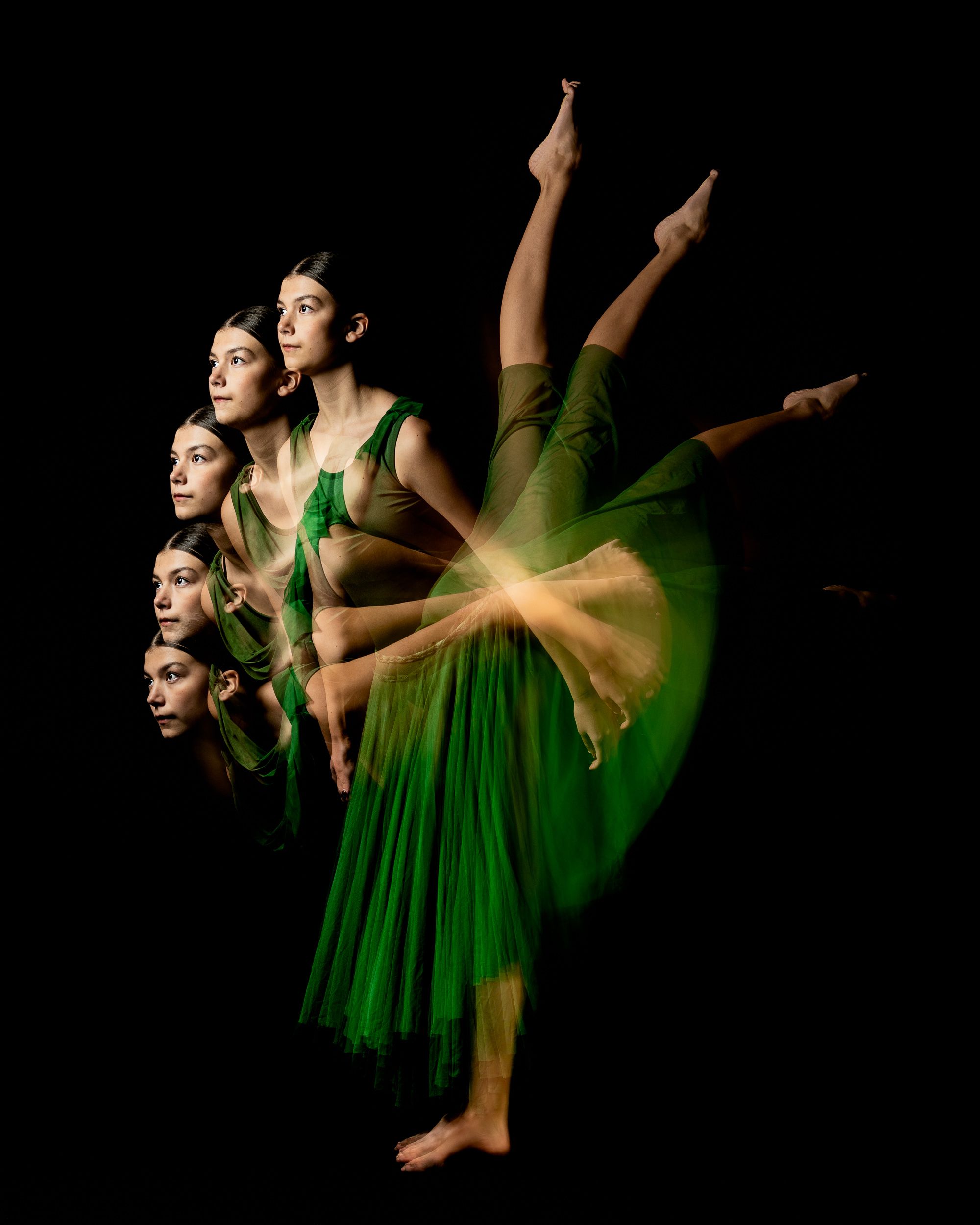 Dancer in green mid-movement with motion trails on a dark stage