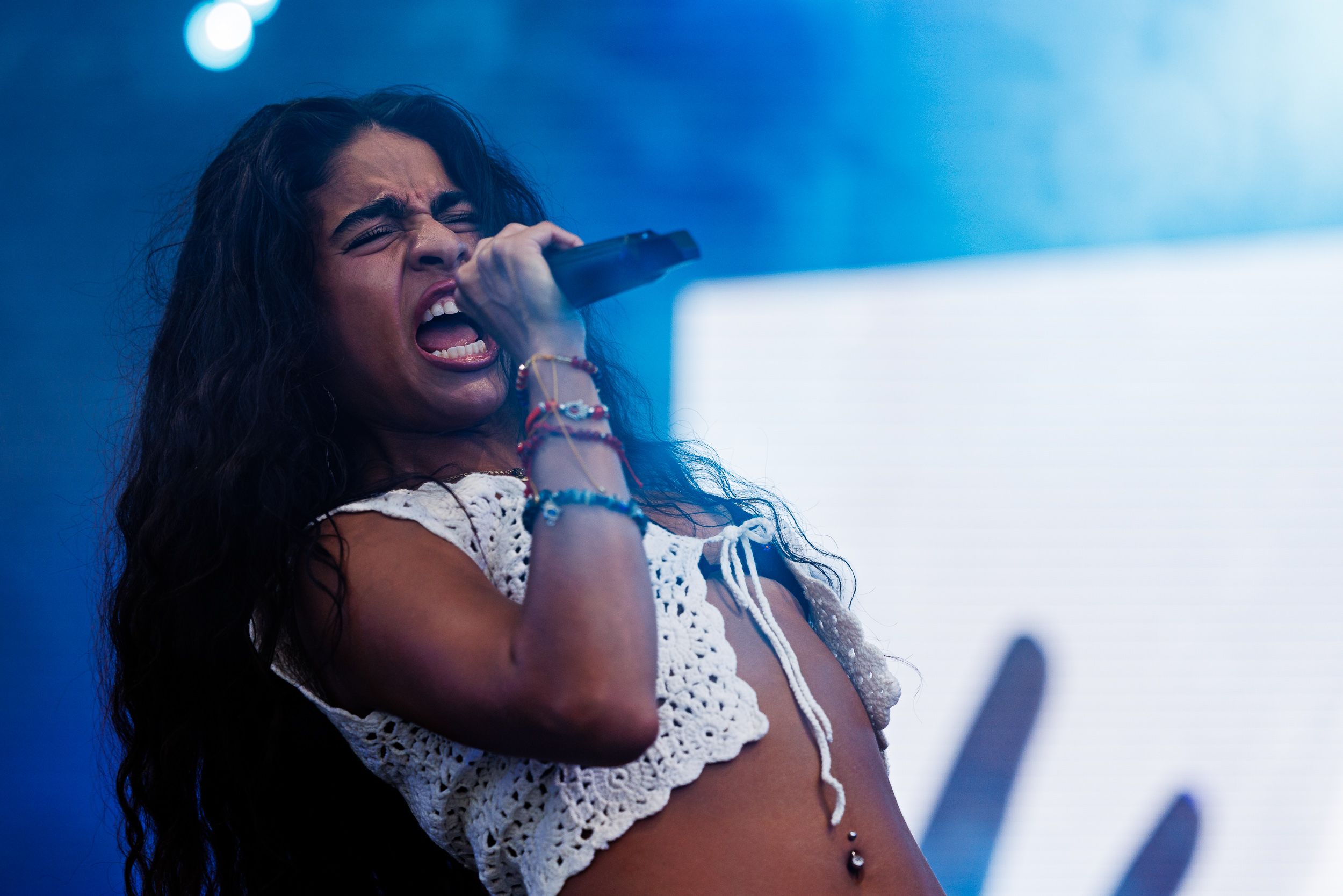 Jessie Reyez on stage in blue concert light