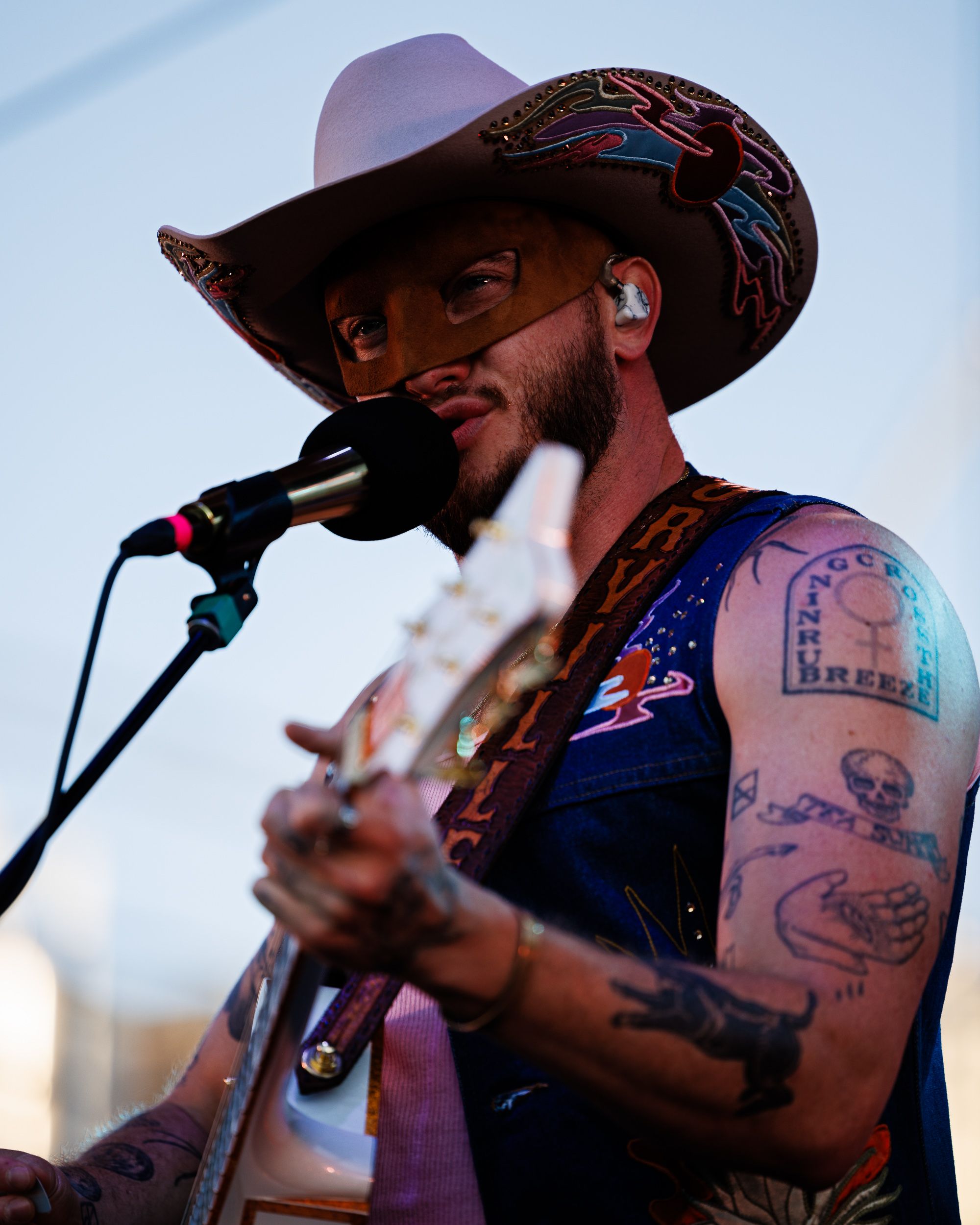 Orville Peck performing live on stage under coloured light