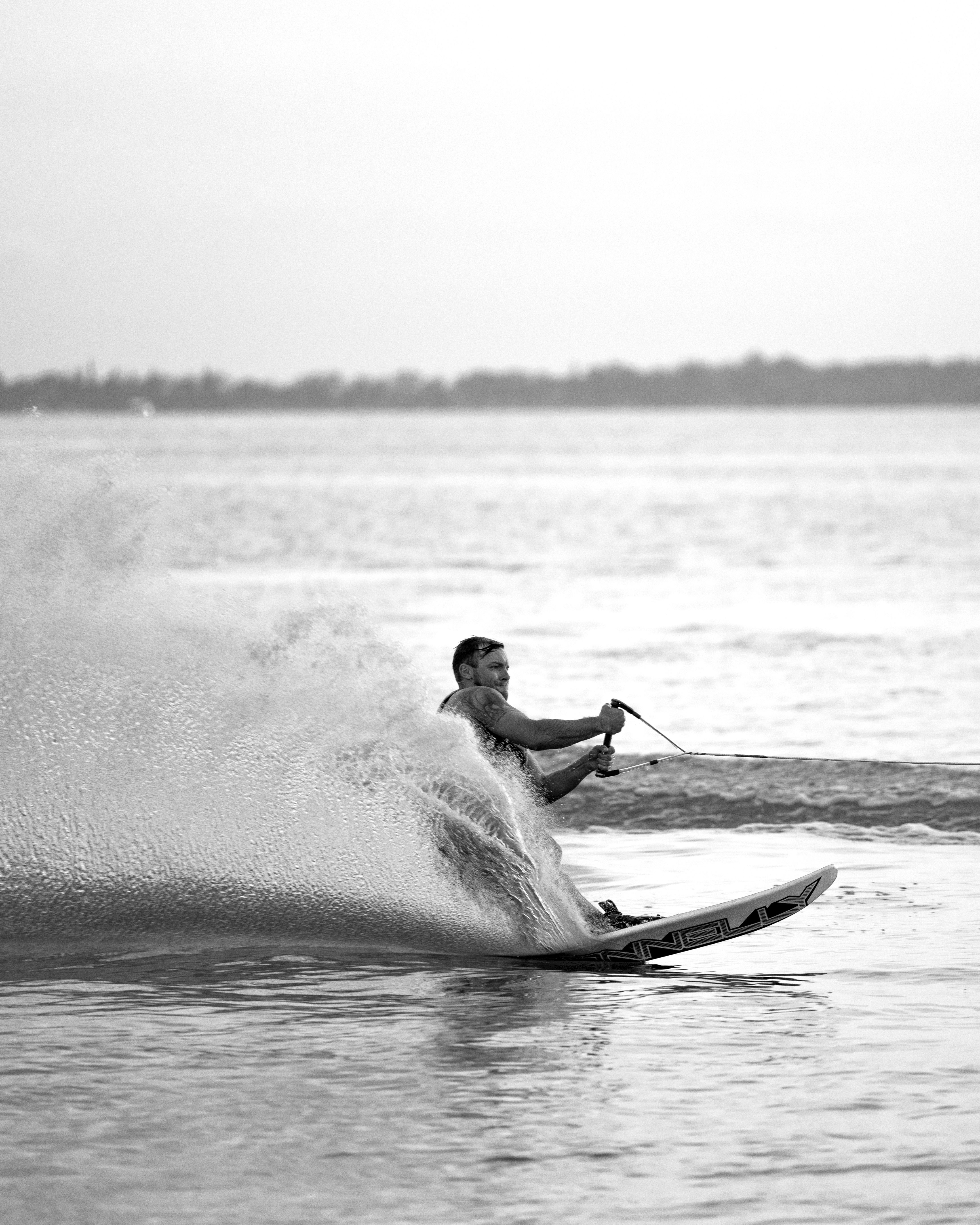 Black and white photograph of a water skier leaning hard into a turn